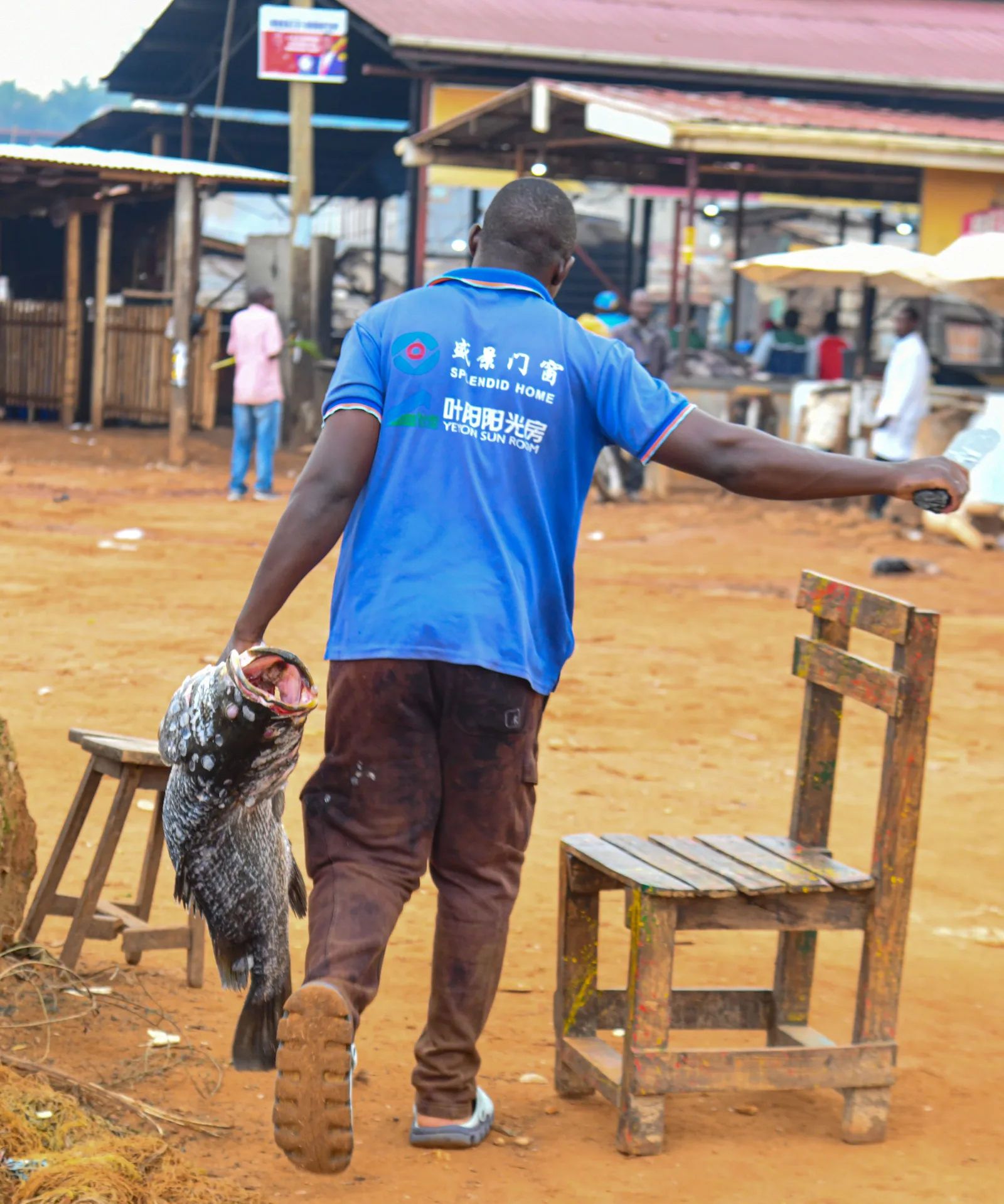 A man carrying a large Nile perch at a Lake Victoria port